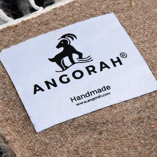 "Close-up of Angorah's handmade label on a mohair rug, showcasing the brand's commitment to craftsmanship. Blog discusses the intricate process of making mohair rugs, from sourcing Angora goat wool to hand-weaving the final product.