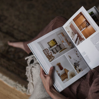 Person reading a home decor magazine while sitting on a mohair rug, illustrating the luxurious and soft texture of mohair, ideal for home interiors. Blog highlights the benefits of mohair rugs for comfort and durability.