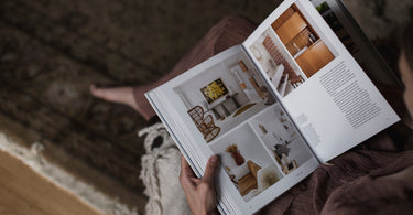 Person reading a home decor magazine while sitting on a mohair rug, illustrating the luxurious and soft texture of mohair, ideal for home interiors. Blog highlights the benefits of mohair rugs for comfort and durability.