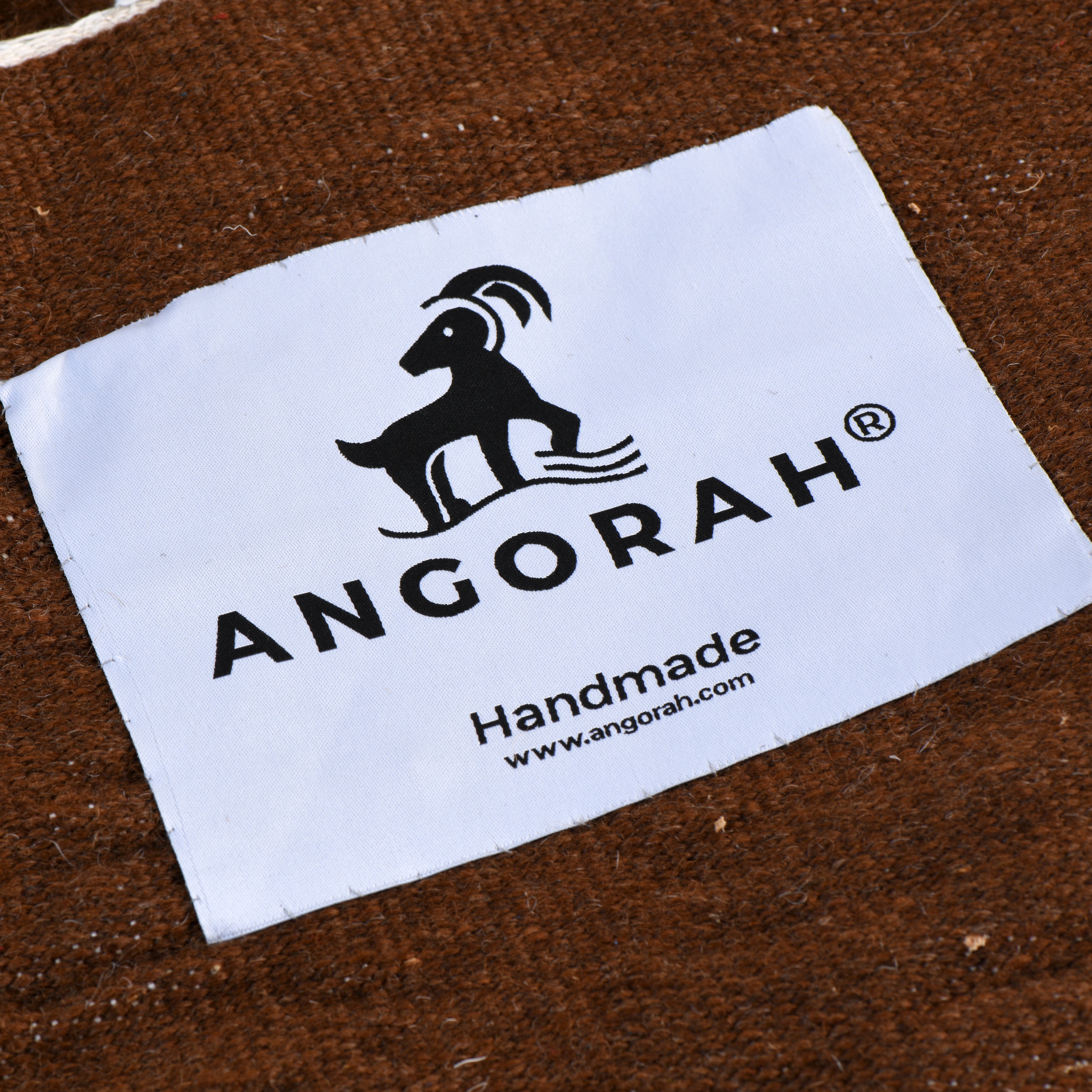 Close-up of the Angorah label on the Marrone organic mohair rug, highlighting the handcrafted quality and rich deep brown color that embodies rustic elegance