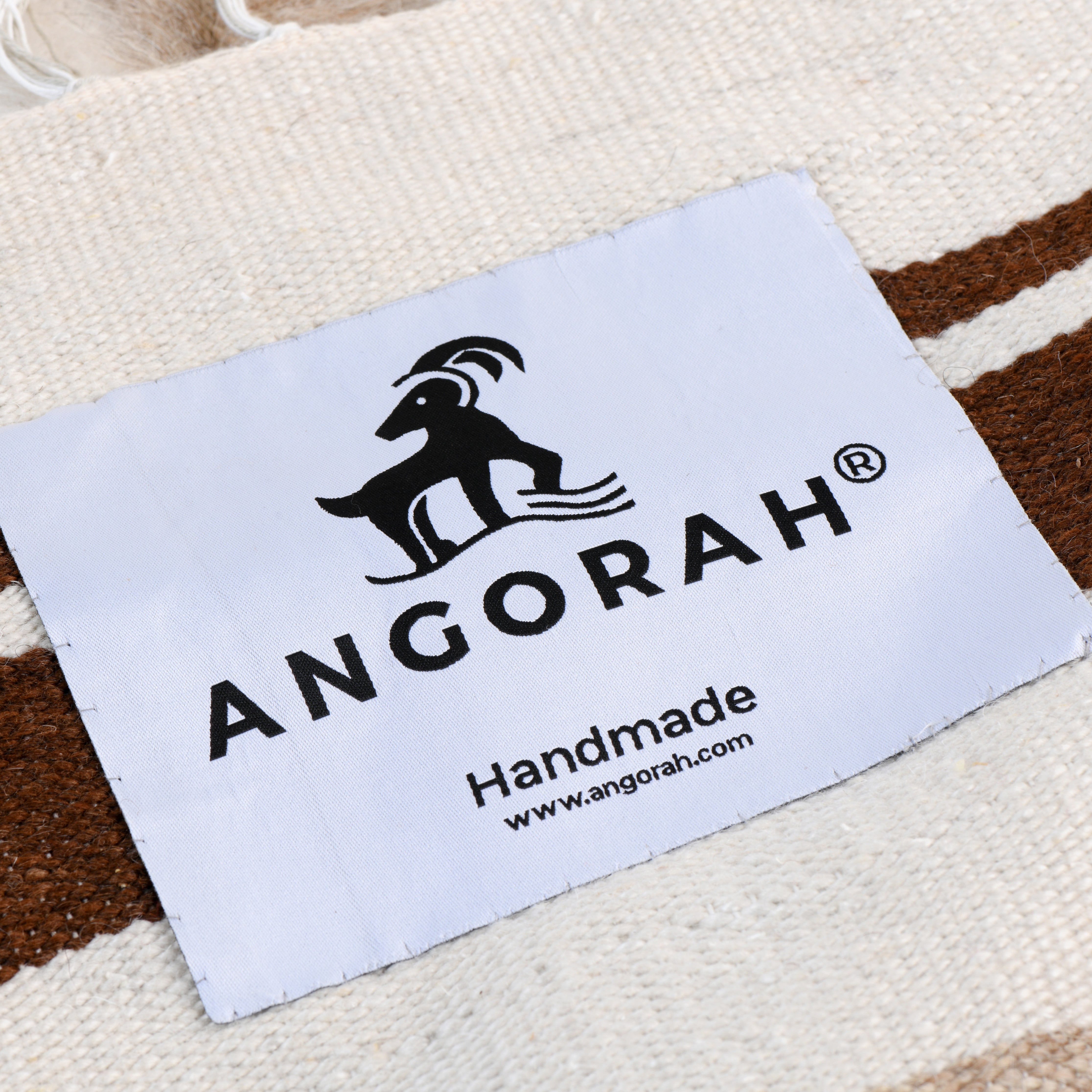 Close-up of the Linjeflod rug label, showcasing the handmade craftsmanship using 100% organic mohair from Angora goats, part of the Scandinavian-inspired design.