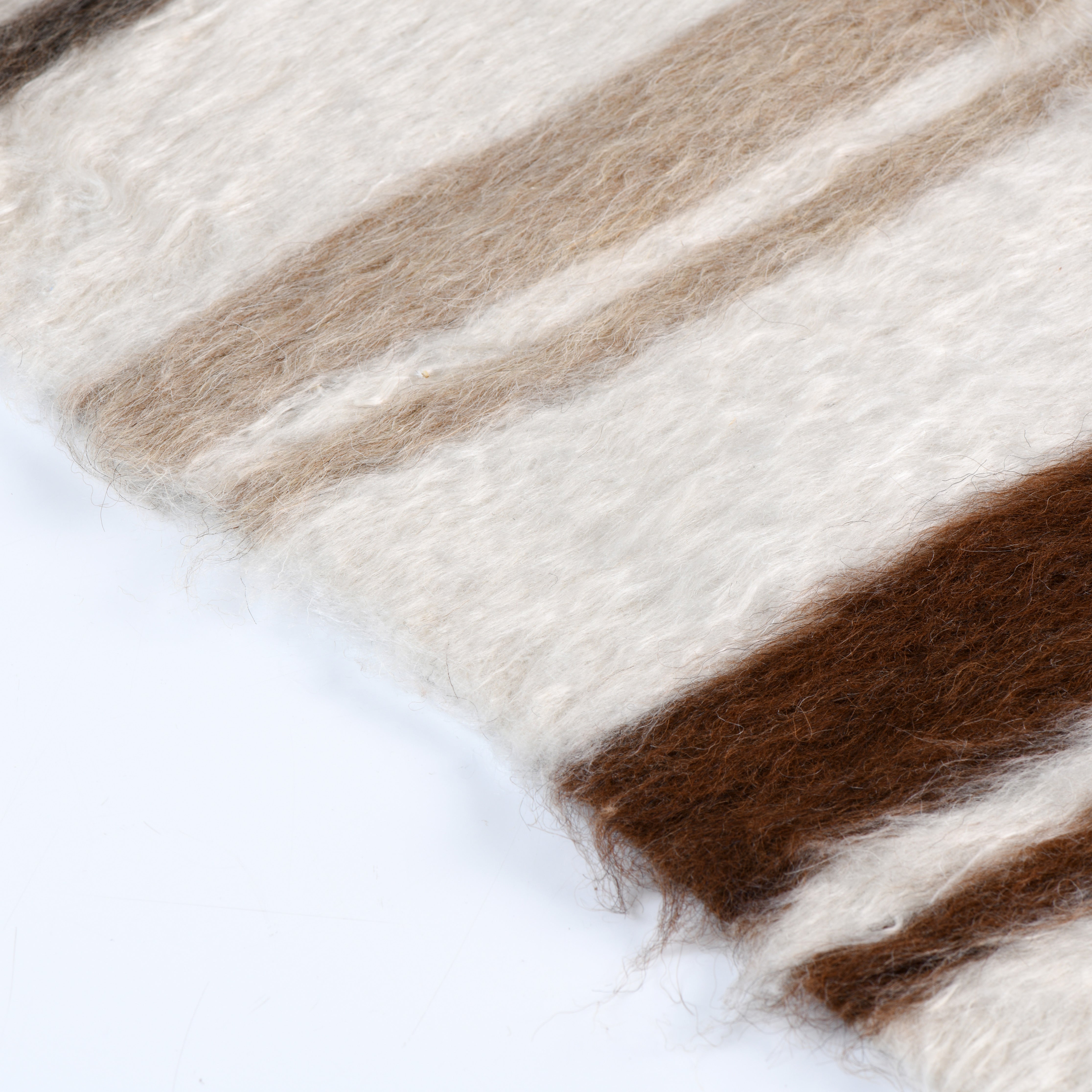 Close-up of the Linjeflod rug edge, showcasing the natural mohair fibers in earthy browns, grays, and whites, handwoven with a Scandinavian design influence