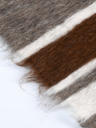 Detailed view of the Skogsfjord rug's edge, showcasing the soft blend of earthy brown, gentle gray, and white stripes, crafted from 100% organic natural mohair